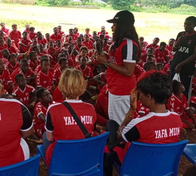 A YAFA Mum addressing a full camp of players seated on the field