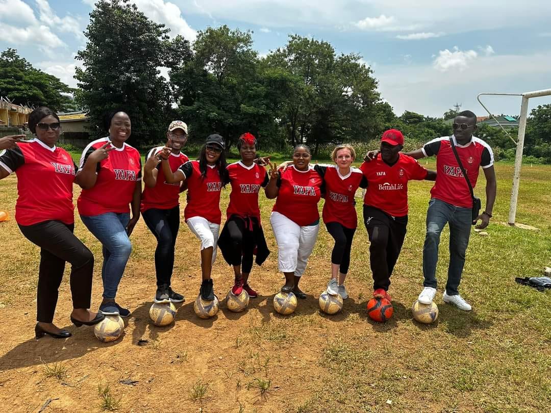 YAFA Mums and Dads in team jerseys standing over footballs at a training ground